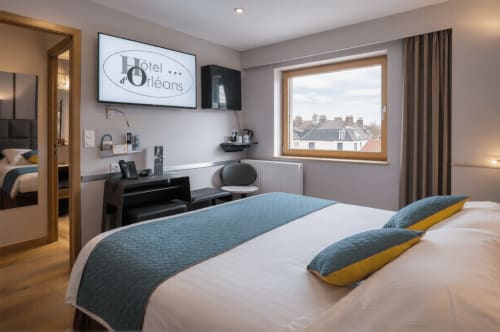 Chambre moderne de l'Hôtel d'Orléans avec accents bleus, bureau et vue sur la ville