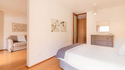 Chambre lumineuse avec lit queen-size, mobilier en bois et coin séjour à l'appartement Flowerstreet54 à Porto