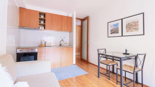 Cuisine et salle à manger modernes d'un studio à Porto avec mobilier en bois, cuisinière et table pour deux