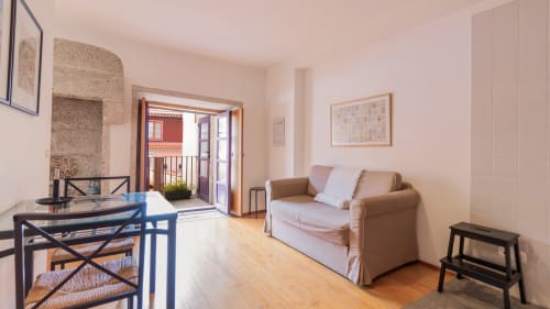 Lumineux séjour à Porto avec canapé beige, table à manger bleue, parquets et accès au balcon.