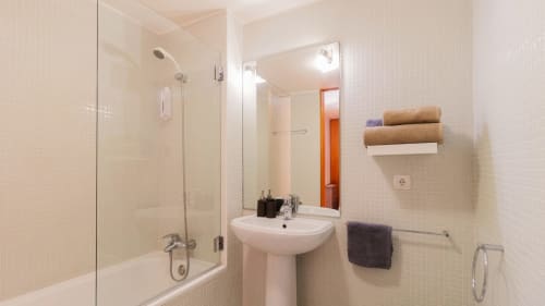 Salle de bain moderne avec douche en verre, lavabo sur piédestal et porte-serviettes en bois à l'appartement Flowerstreet54 à Porto