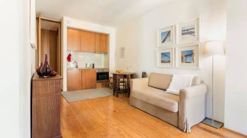 Petit studio cosy à Porto avec cuisine en bois, canapé crème, parquet et vue sur la ville en photos