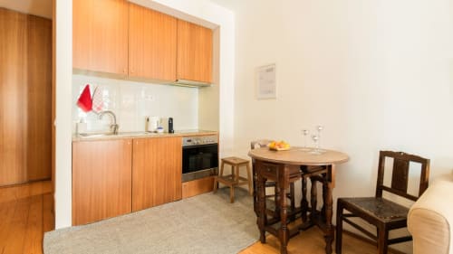 Cuisine moderne et salle à manger dans un appartement de Porto avec meubles en bois, cuisinière et table pour recevoir les invités