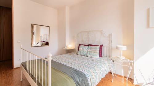 Chambre lumineuse à Flowerstreet54 à Porto avec lit en fer blanc, literie rayée, miroir et parquet