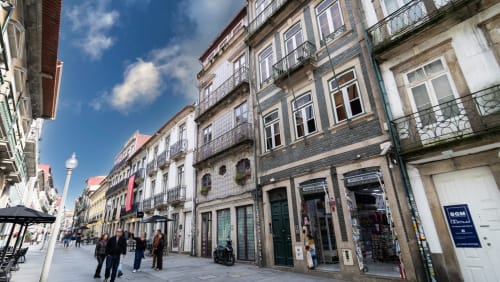 Rue pittoresque de Porto avec bâtiments colorés, azulejos bleus et passants, près de l'appartement Flowerstreet54 avec vue sur la ville.