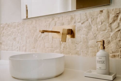 Modern bathroom vanity at Villa Merida with white vessel sink, brass fixtures, and hand soap dispenser.