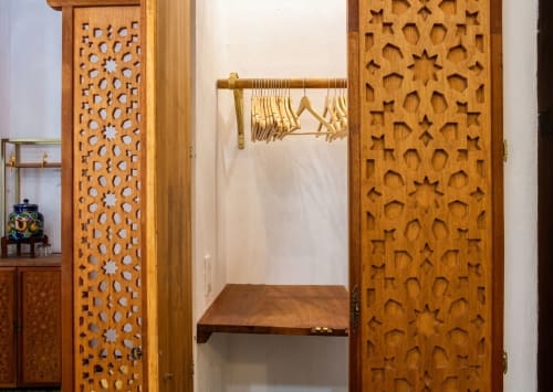 Wooden carved closet doors with brass rod and hangers in Villa Merida Boutique Hotel room, Merida Mexico
