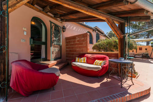 Lettini rossi sulla terrazza di Villa Verde a Torre delle Stelle, Italia, con pergolato in legno e architettura rustica