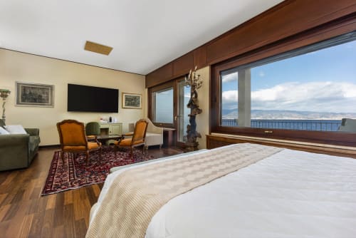 Lussuosa camera a Reggio Suite B&B con balcone vista mare, arredi eleganti e panorama della Calabria costiera