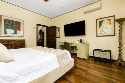 Camera elegante della Reggio Suite Luxury B&B a Reggio Calabria con letto bianco, pareti color crema, pavimenti in legno e design moderno