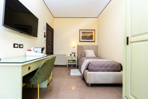Camera moderna di Reggio Suite Luxury B&B a Reggio Calabria con letto, scrivania, TV e illuminazione calda