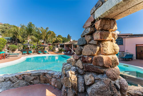 Piscina turchese con scultura di pietre impilate presso Villa Verde a Torre delle Stelle, Italia
