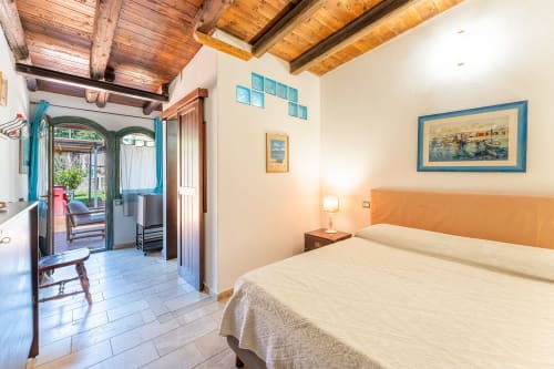 Camera spaziosa a Villa Verde con letto queen, testata arancione, travi in legno e porte con vista sul giardino a Torre delle Stelle