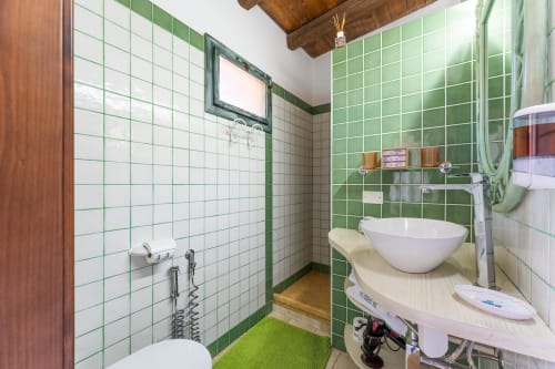 Bagno moderno con piastrelle verde e bianche, lavabo a bacinella e doccia presso la guest house Villa Verde a Maracalagonis
