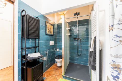 Bagno moderno con pareti in piastrelle azzurre, doccia walk-in e mobili contenitori neri presso Villa Verde, casa vacanze in Sardegna