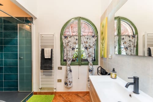 Bagno moderno a Villa Verde a Maracalagonis con piastrelle turchesi, specchi archeati con cornice verde e