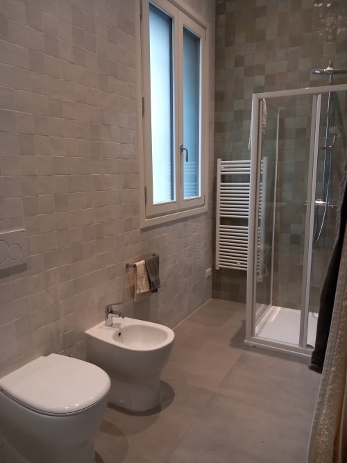 Bagno moderno dell'Albergo Giulia Gonzaga con wc, bidet, doccia walk-in, scaldasalviette e finestra con vista sulla città