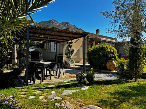 Jardin de villa corse avec terrasse ombragée, espace repas et vue sur les montagnes à L'Île-Rousse