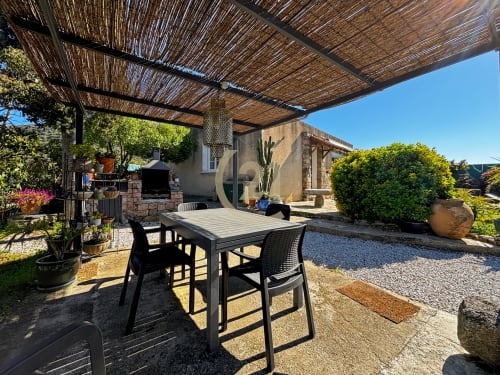 Terrasse de villa méditerranéenne avec table à manger, pergola, barbecue et jardin à L'Île-Rousse