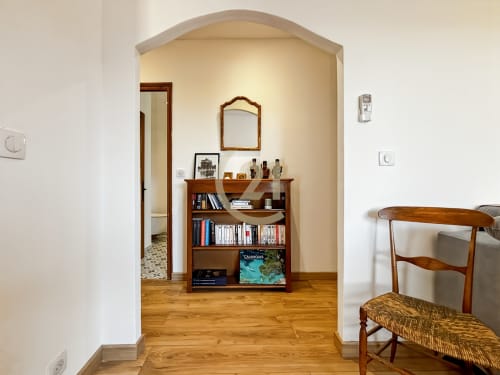 Élégant salon de villa avec bibliothèque en bois, alcôve cintrée et fauteuil tissé à L'Île-Rousse