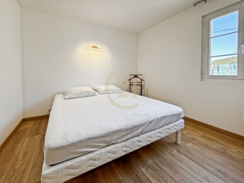 Chambre lumineuse avec literie blanche, parquet et vue sur le jardin à la villa Century 21 de L'Île-Rousse