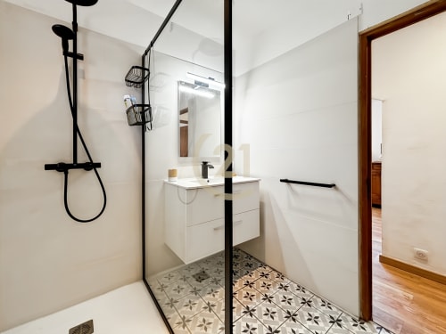 Salle de bains moderne avec fixtures noires, vasque blanche, carrelage géométrique et douche à l'italienne à la villa de L'Île-Rousse