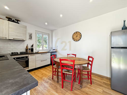 Cuisine-salle à manger moderne avec chaises rouges, table en bois et électroménagers en acier inoxydable dans la villa de L'Île-Rousse