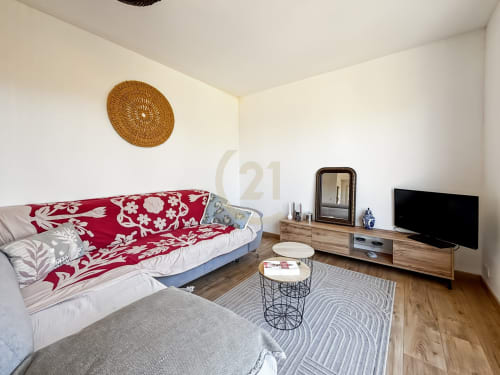 Chambre moderne de villa à L'Île-Rousse avec parure florale rouge, TV, mobilier en bois et décoration murale tissée