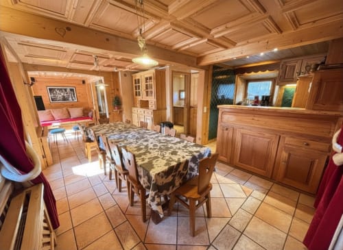 Spacious dining area in Chalet Marie Claire at Chez Francine with wooden beams, table, chairs, and adjacent living spaces