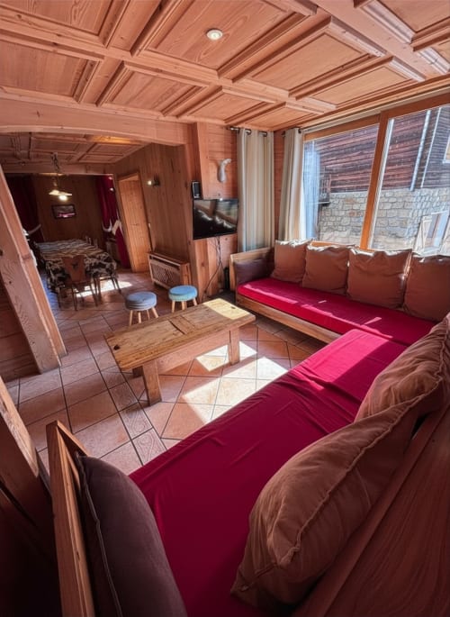 Chalet Marie Claire living room with wooden coffered ceiling, burgundy seating, mountain views, and modern TV at Chez
