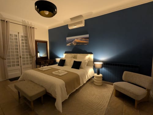 Chambre élégante à La Closerie B&B à La Redorte avec mur d'accent bleu marine, literie crème et éclairage moderne.