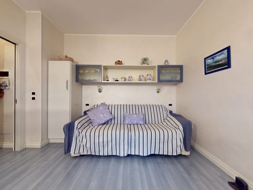 Modernes Schlafzimmer im Hotel Come a Casa Tua in Mailand mit gestreiftem Sofa, blau gerahmten Regalen und Fernseher mit Stadtblick
