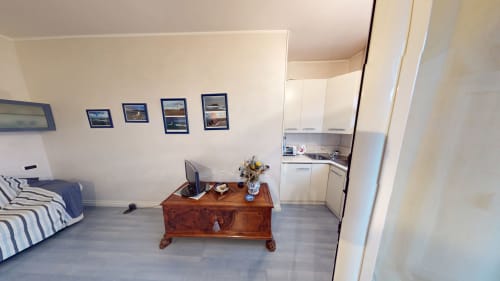 Marghera Studiowohnung in Milano mit Küchenzeile, Holzschreibtisch, Bett und Stadtfotos an der Wand