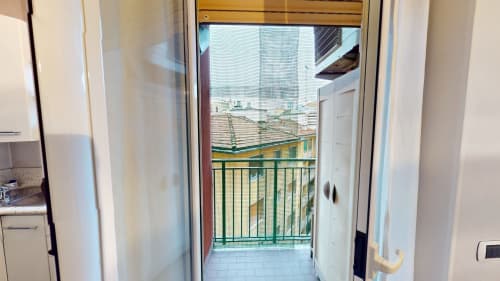 Glastür, die zum privaten Balkon mit grünem Geländer mit Ausblick auf die Mailänder Skyline der Wohnung Come a Casa Tua führt