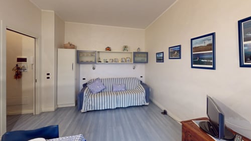 Geräumiges Schlafzimmer einer Mailänder Wohnung mit gestreiftem Sofa, Küstenkunst, Schränke und Parkettboden im Come a Casa