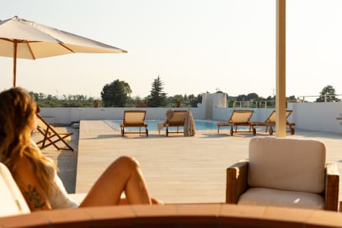 Donna che si rilassa in piscina sul tetto di Villa Ceci ad Andria con lettini e ombrelloni