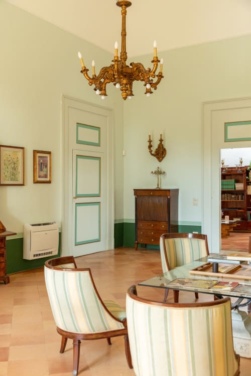 Elegante salotto di Villa Ceci B&B ad Andria con sedie rigate, lampadario dorato ornamentale e arredi d'epoca