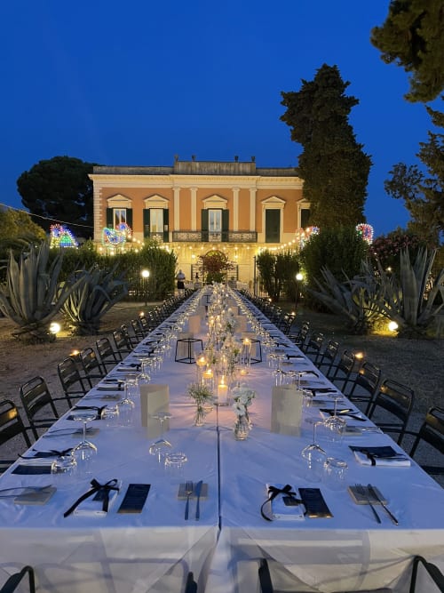 Elegante cena all'aperto presso Villa Ceci B&B ad Andria, Italia: tavolo lungo, candele e edificio storico al tramonto