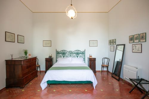 Camera Cristina King Deluxe di Villa Ceci ad Andria con letto in ferro battuto, pavimenti in cotto e vista sul giardino