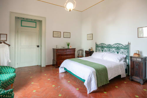 Camera da letto elegante a Villa Ceci B&B ad Andria con testata ornamentale verde, pavimenti in terracotta e vista sul giardino