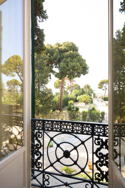 Elegante balconata nera con vista sui lussureggianti giardini mediterranei di Villa Ceci, Andria
