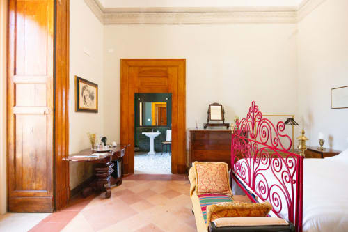 Camera Vittoria Junior Suite a Villa Ceci ad Andria con elegante testata rossa, porte in legno, pavimenti in cotto