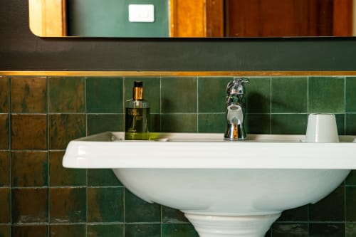 Lavabo vintage con rivestimento in piastrelle verdi, rubinetto cromato e articoli da toilette alla Villa Ceci B&B ad Andria, Italia