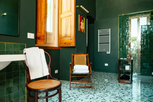 Bagno elegante di Villa Ceci con pareti verde scuro, mobili in legno, pavimento in terrazzo, sedie vintage e dettagli moderni