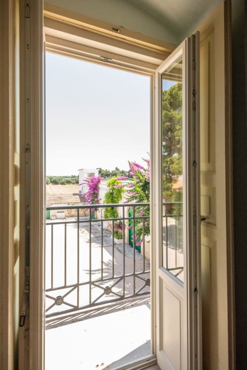 Porte-finestre aperte dallo studio di Medicina di famiglia di Villa Ceci ad Andria rivelano bouganvillea fiorite e viste sulla campagna