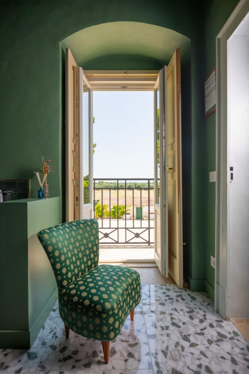 Camera da letto verde a Villa Ceci con sedia decorata, soffitto a volta e porte-finestre aperte verso il balcone giardino