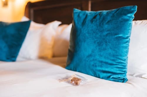 Letto con cuscini in velluto turchese e biancheria bianca alla guest house Vento del Sud in Italia