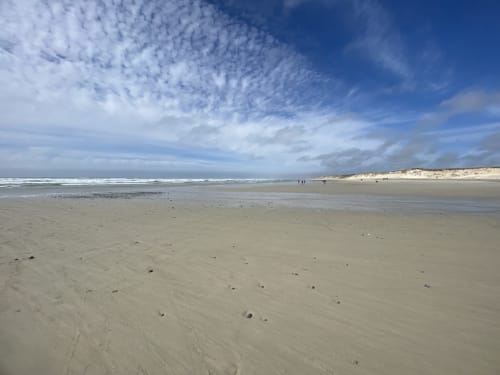 Wide sandy beach with calm waters and dunes at Le Lama Zébré in Penmarch, France