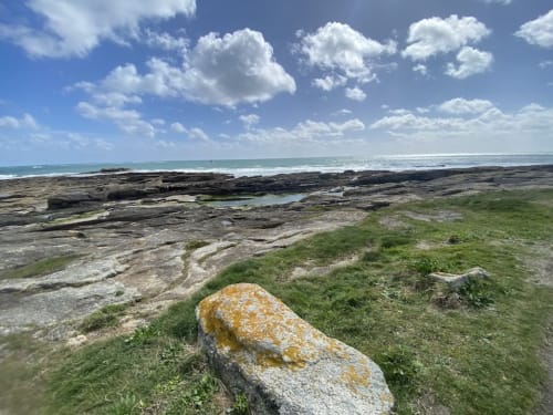 Rocky coastal landscape at Le Lama Zébré in Penmarch with green fields and ocean horizon