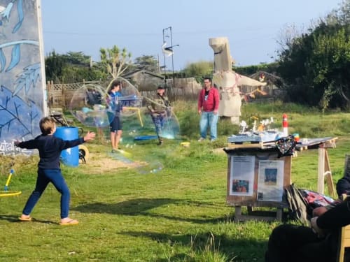 Children playing with bubbles at Le Lama Zébré's outdoor garden area in Penmarch, France during a fun activity day